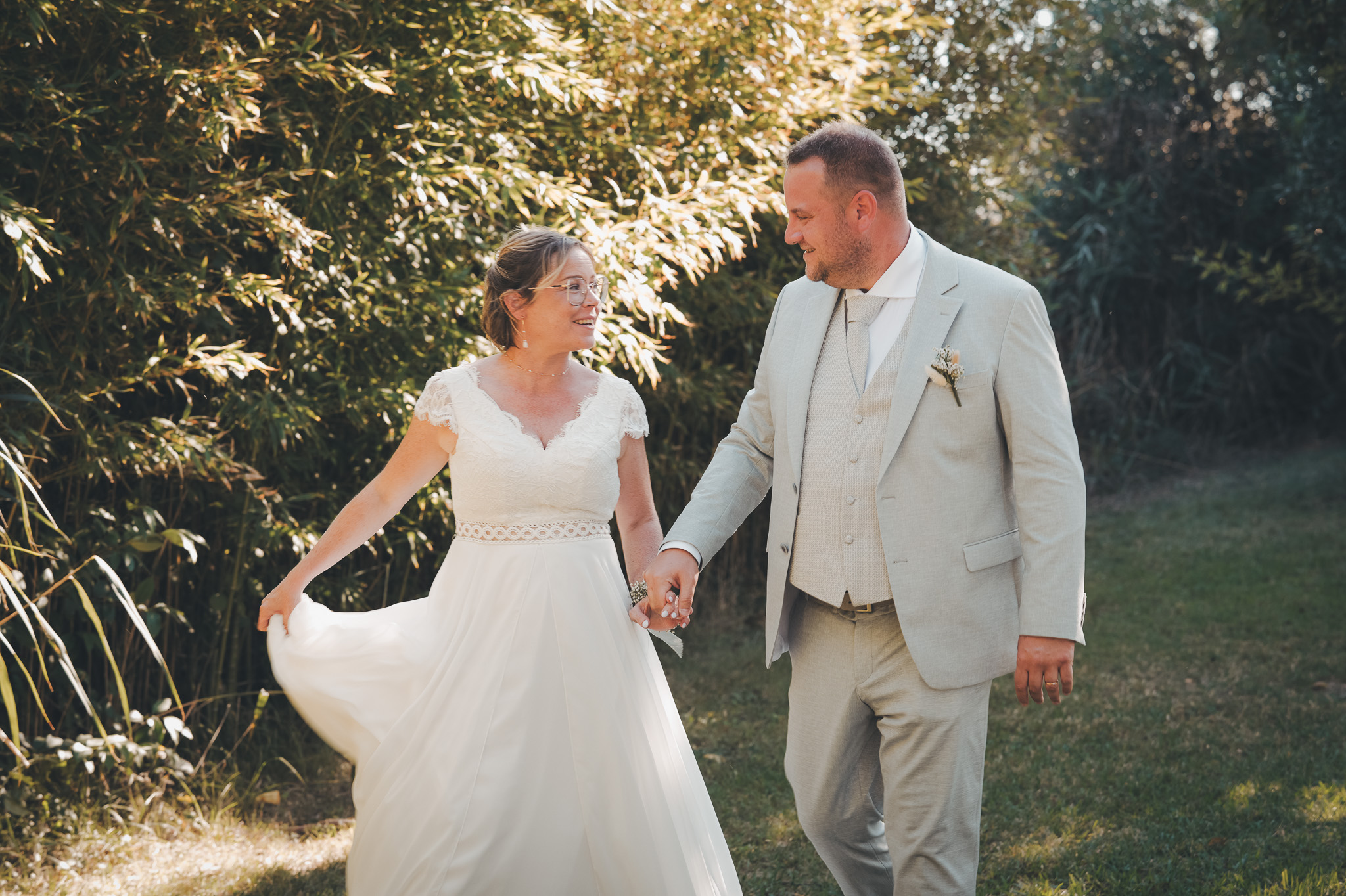 The newlyweds exchange a glance as they walk, the bride lifting her dress slightly.