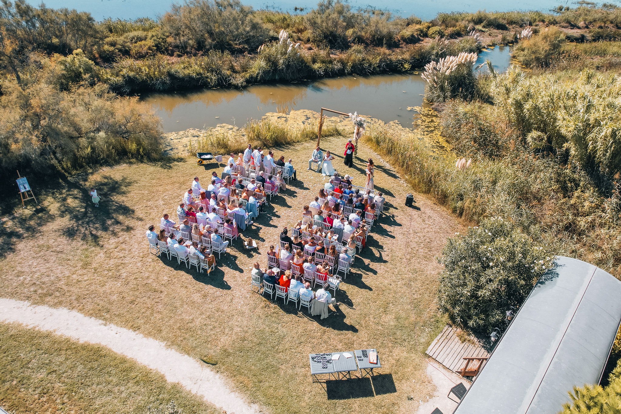 An aerial view of the wedding ceremony beside the water, surrounded by vegetation.