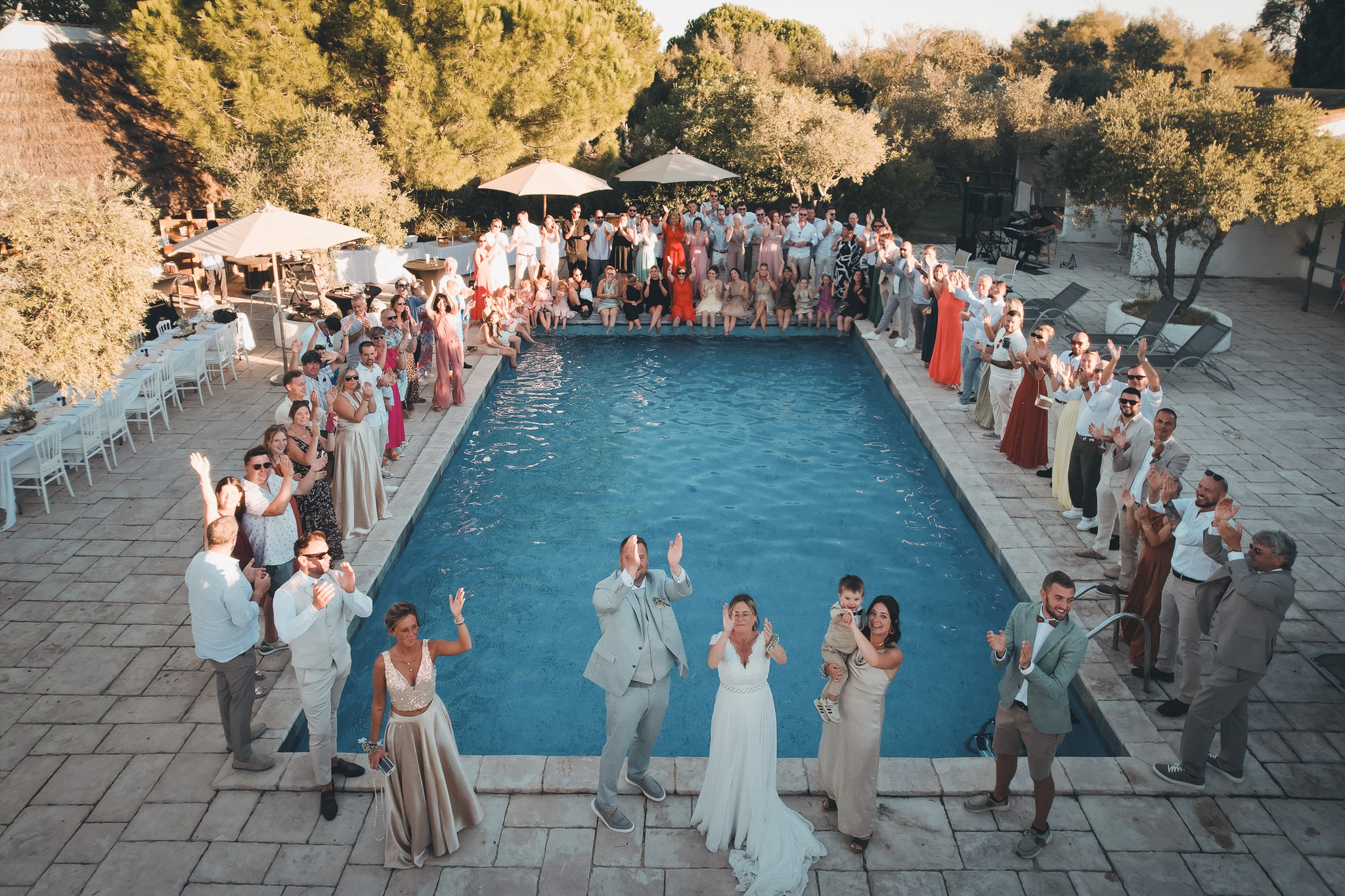 An elevated view of the newlyweds and their guests gathered around a swimming pool.