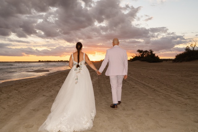 The couple walking hand in hand towards the evening light.